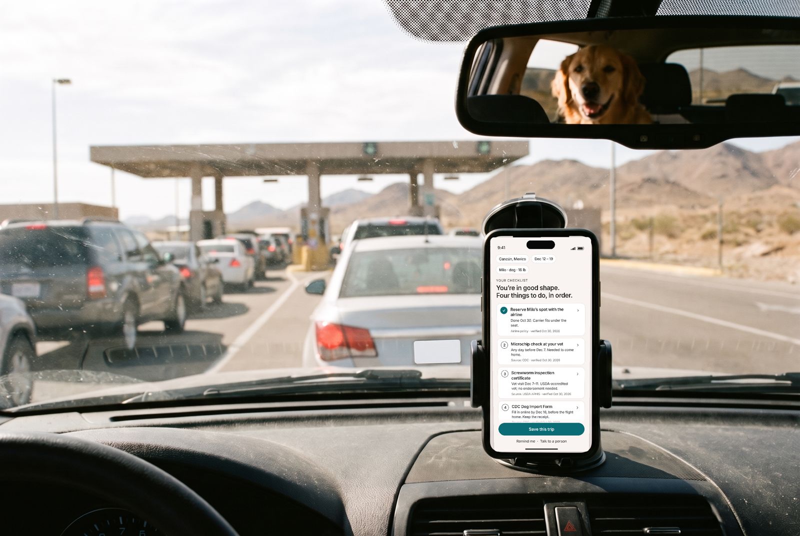 A phone on a dashboard mount shows a checklist while a car waits in the US–Mexico border line